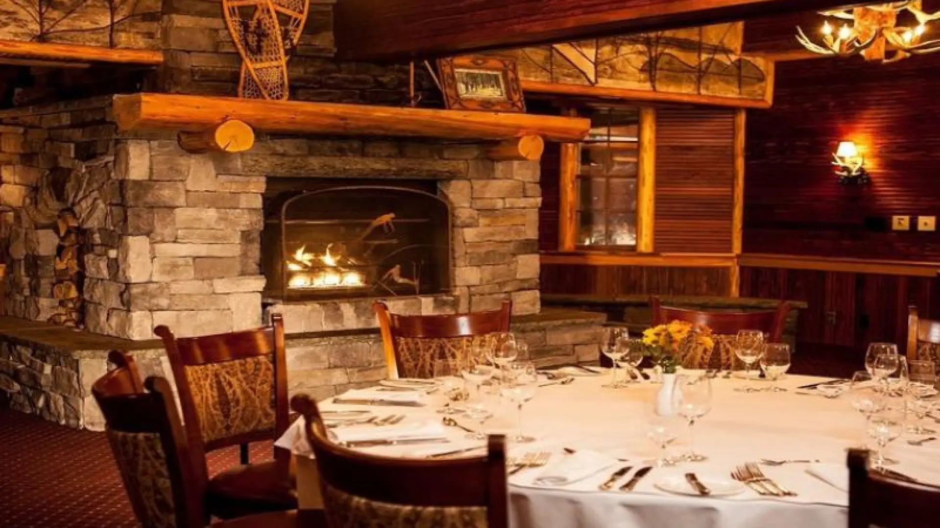 A lodge-style dining room with a large stone fireplace.