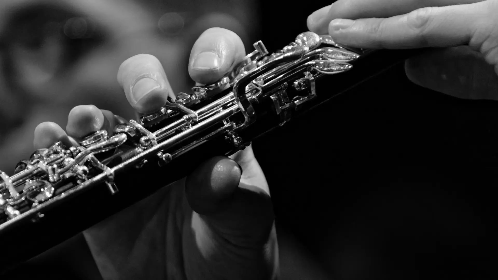 Black and white stock image of a person's hands holding an oboe