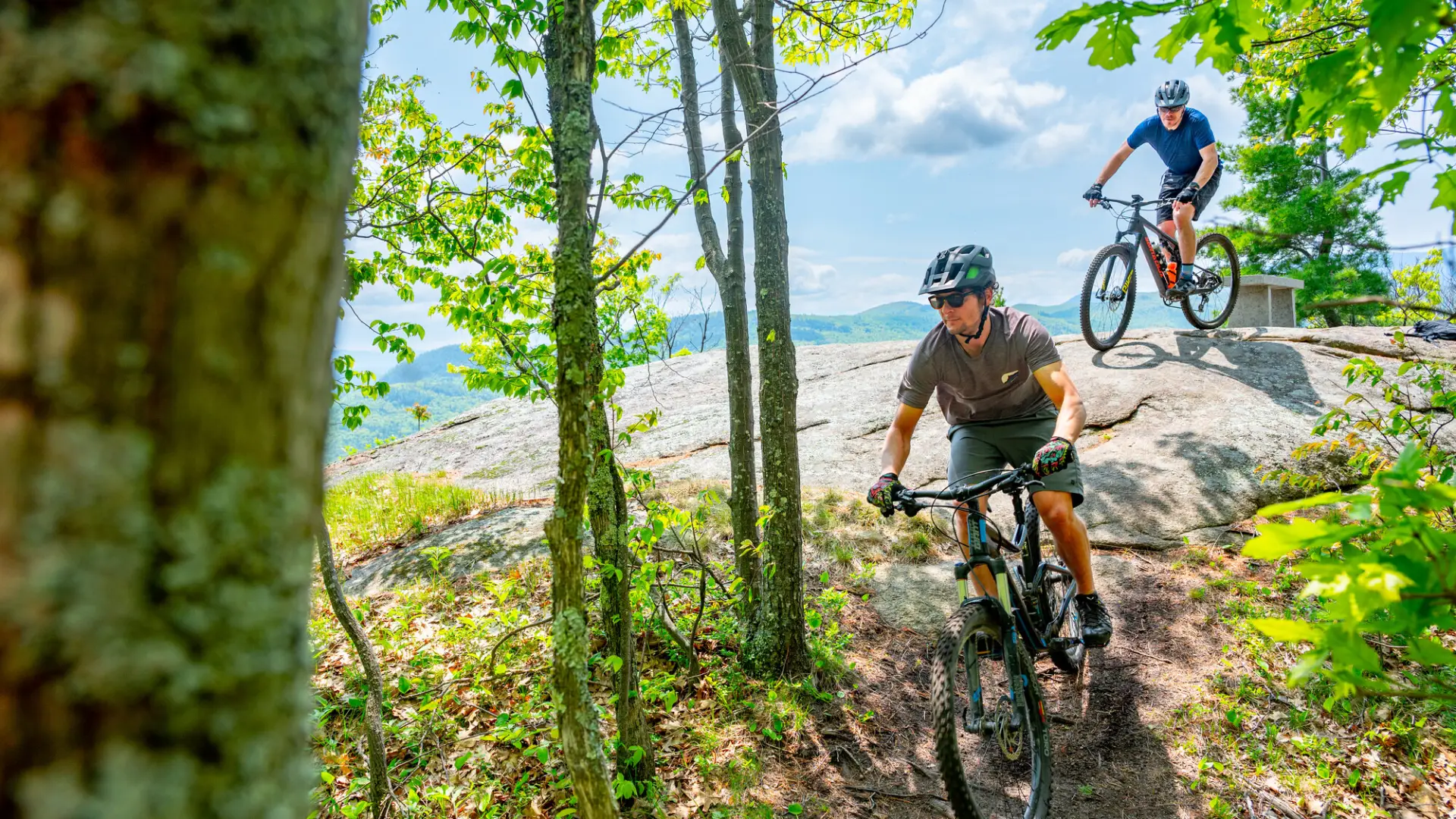 A couple mountain bikers leaving a rocky cliff