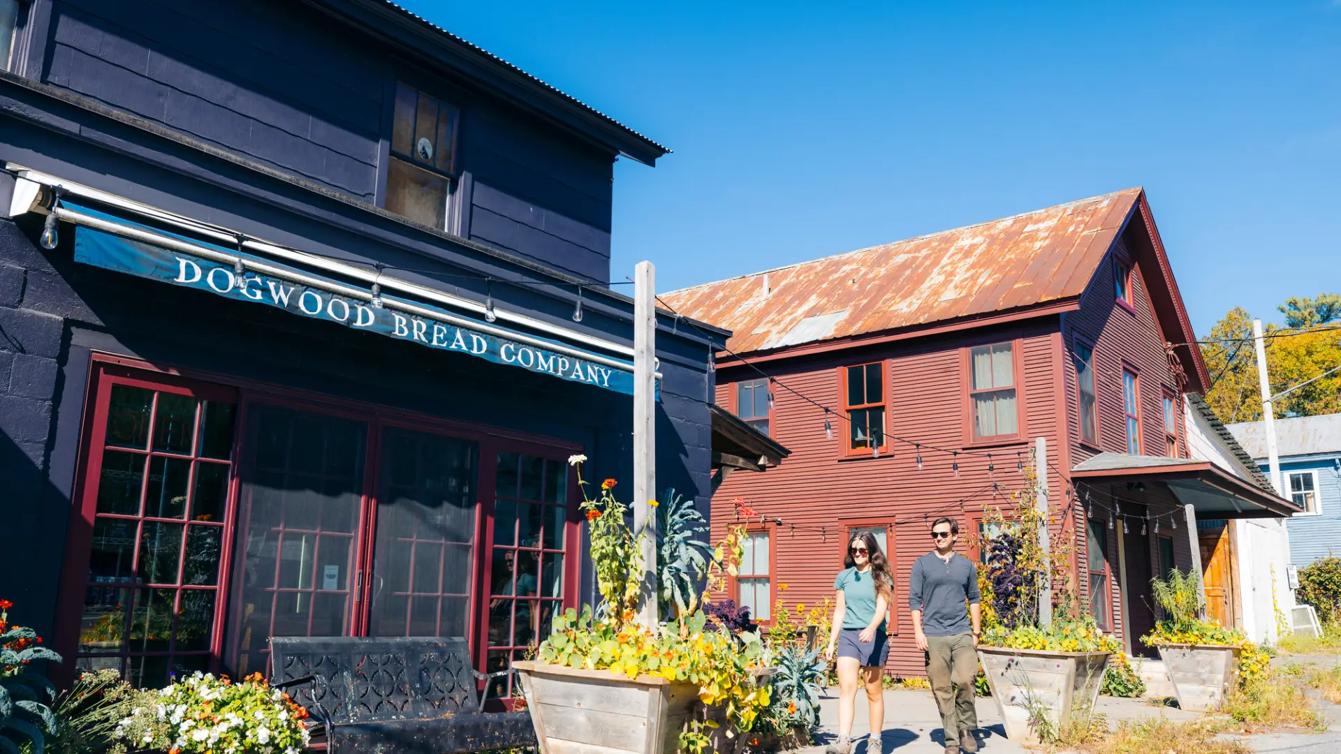A man and woman walk to a restaurant on a sunny day. 