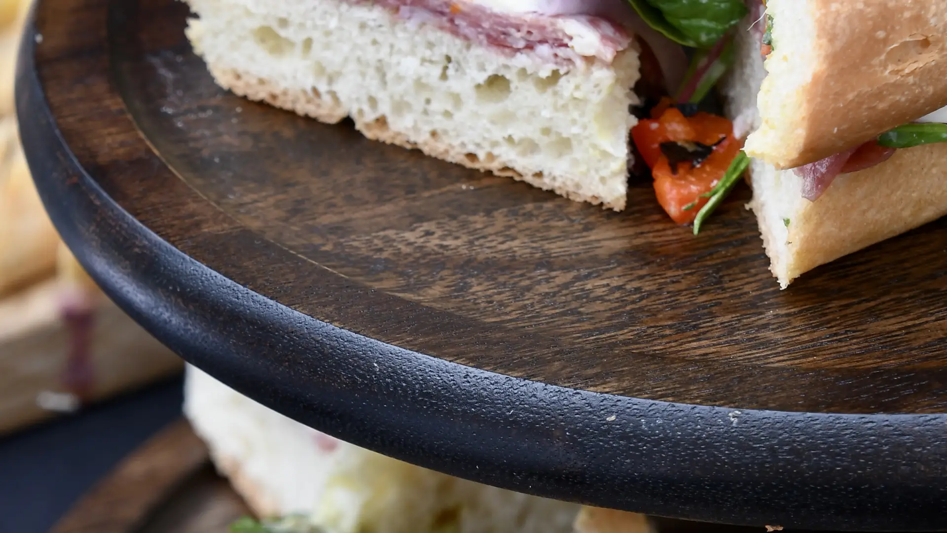 Tiered dark wooden platter with small sandwich triangles