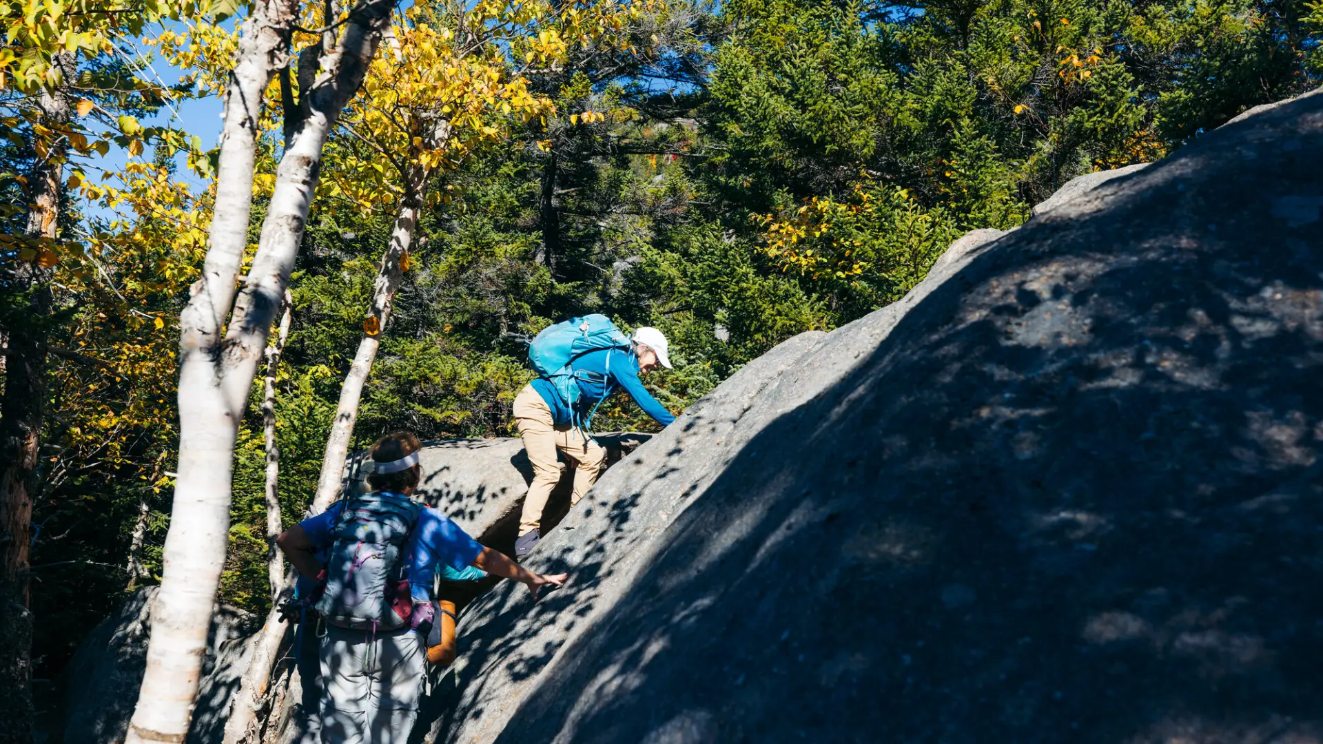 An older hiker going up a short rock face