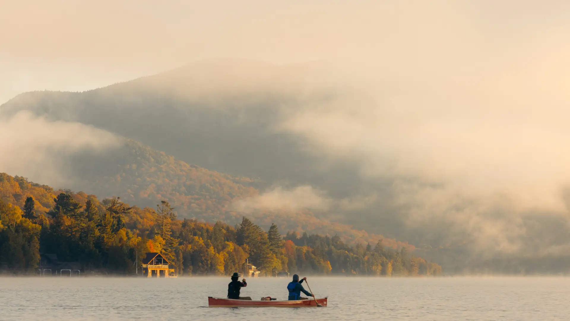 Two people canoe on an early morning lake.
