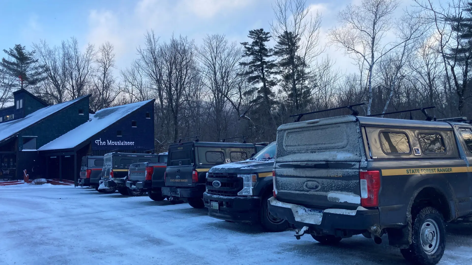 Line of NYS Forest Ranger trucks covered in frost lined up in parking lot of Mountaineer store in winter