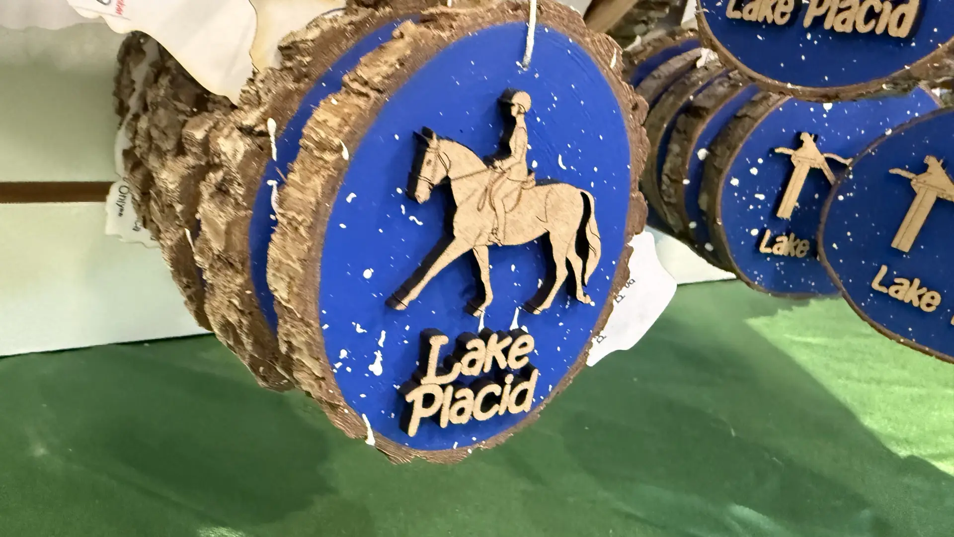A lake placid themed log cookie ornament with a person riding a horse.