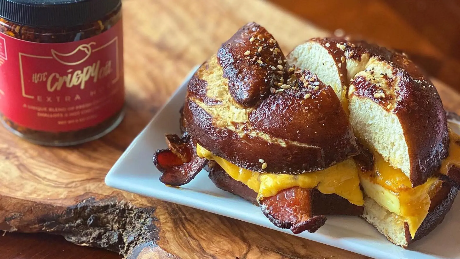 A bacon egg and cheese sandwich on a pretzel bun on a plate.