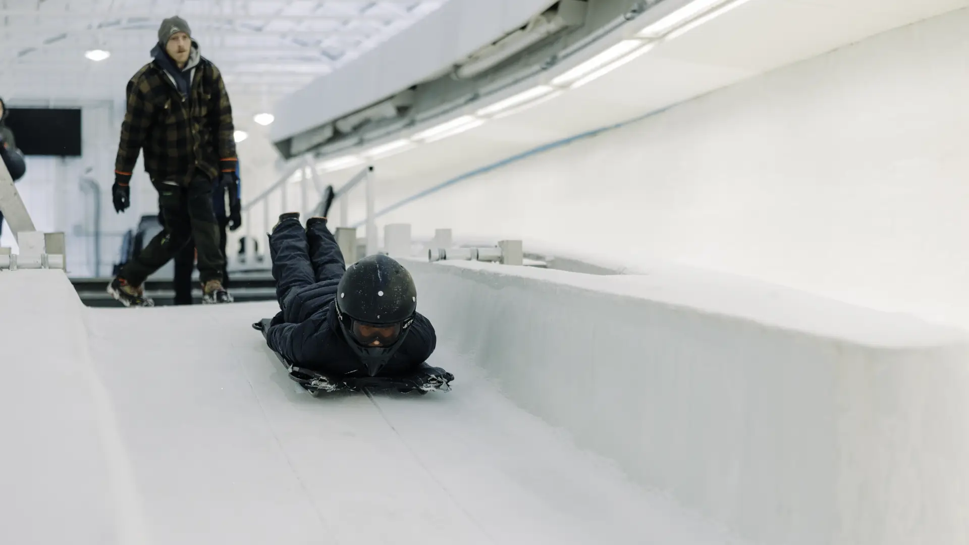 Person slides down ice track head first on skeleton sled