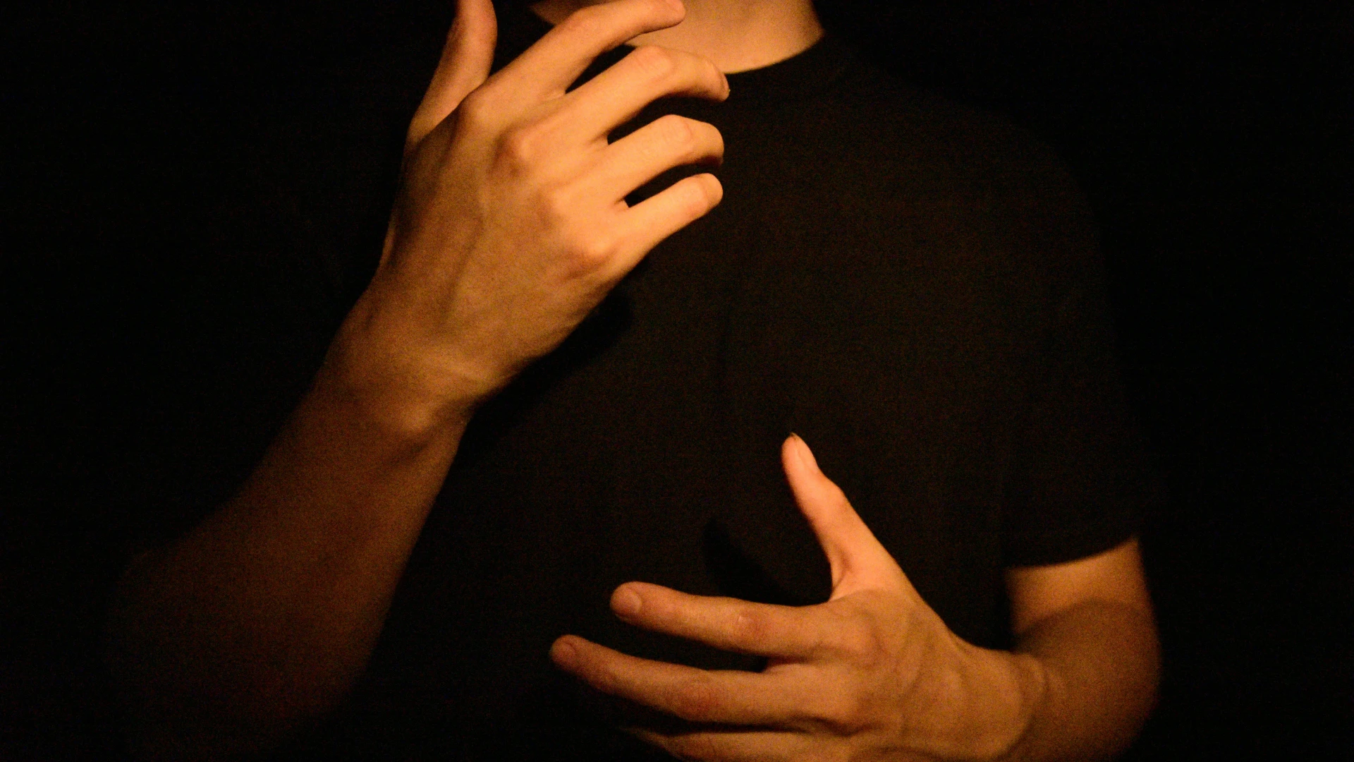 Stock image of person in black shirt signing with their hands with only their hands and forearms visible.
