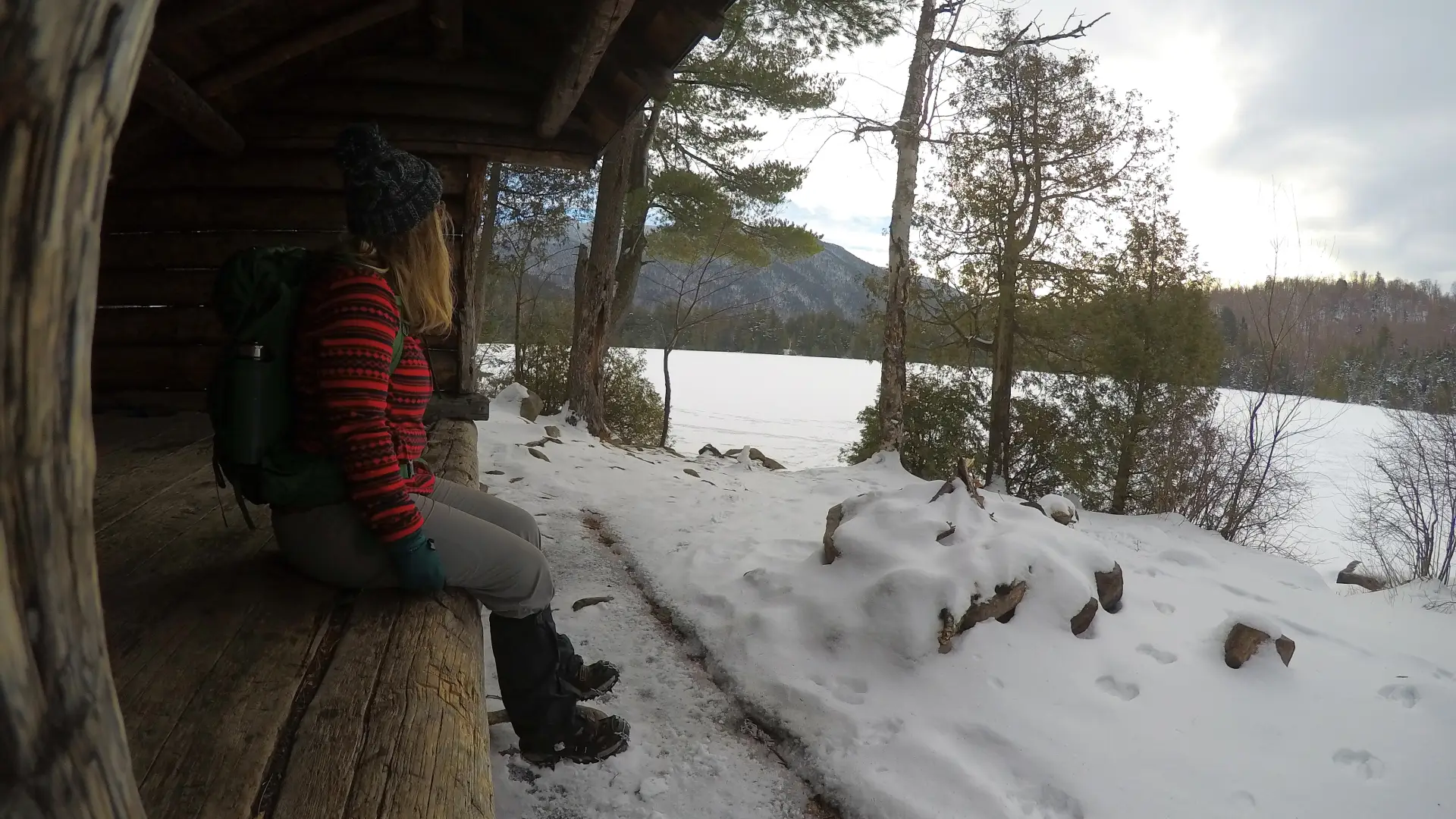 A person sitting at a lean-to in the winter