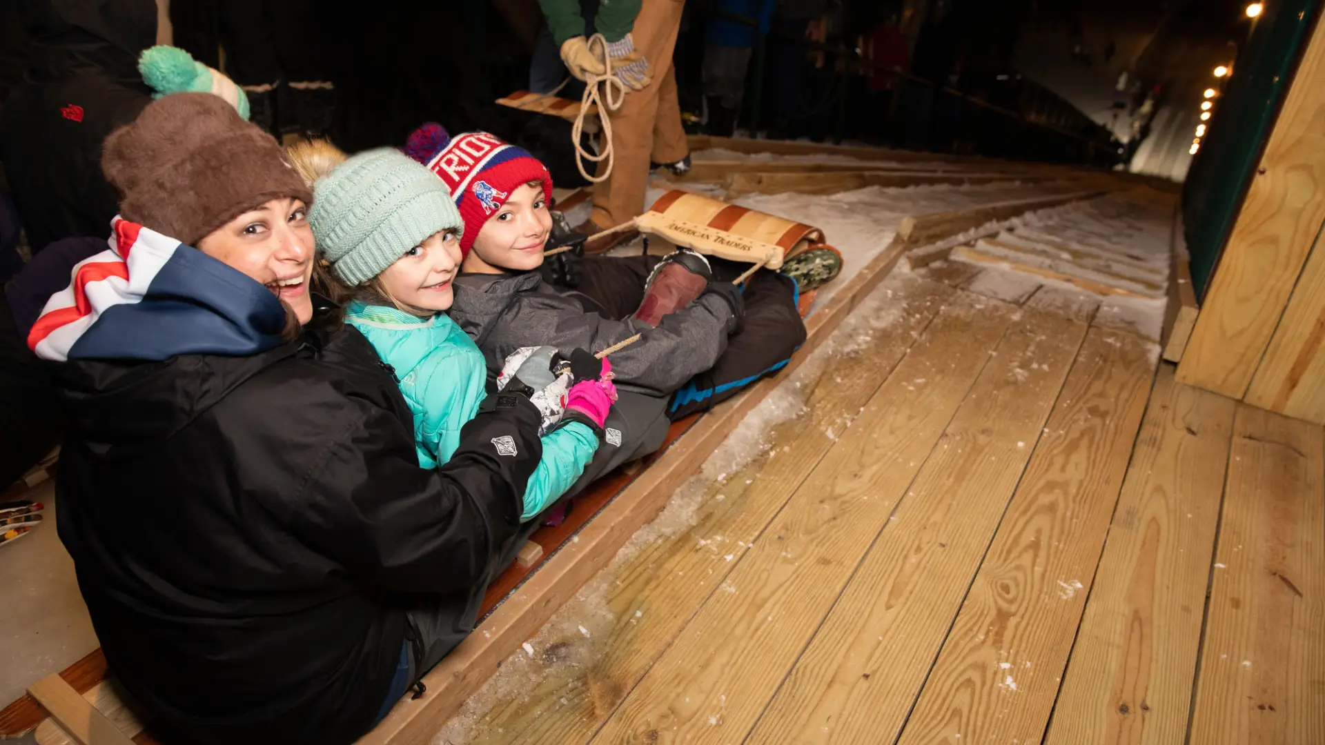 A woman and two children prepare to slide down the toboggan chute.