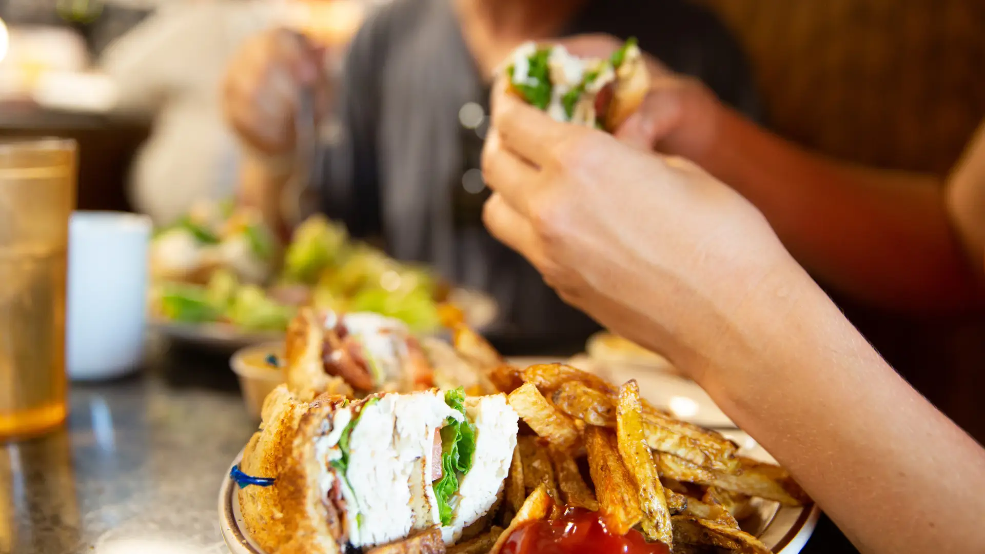 A person takes a bite out of a club sandwich. 