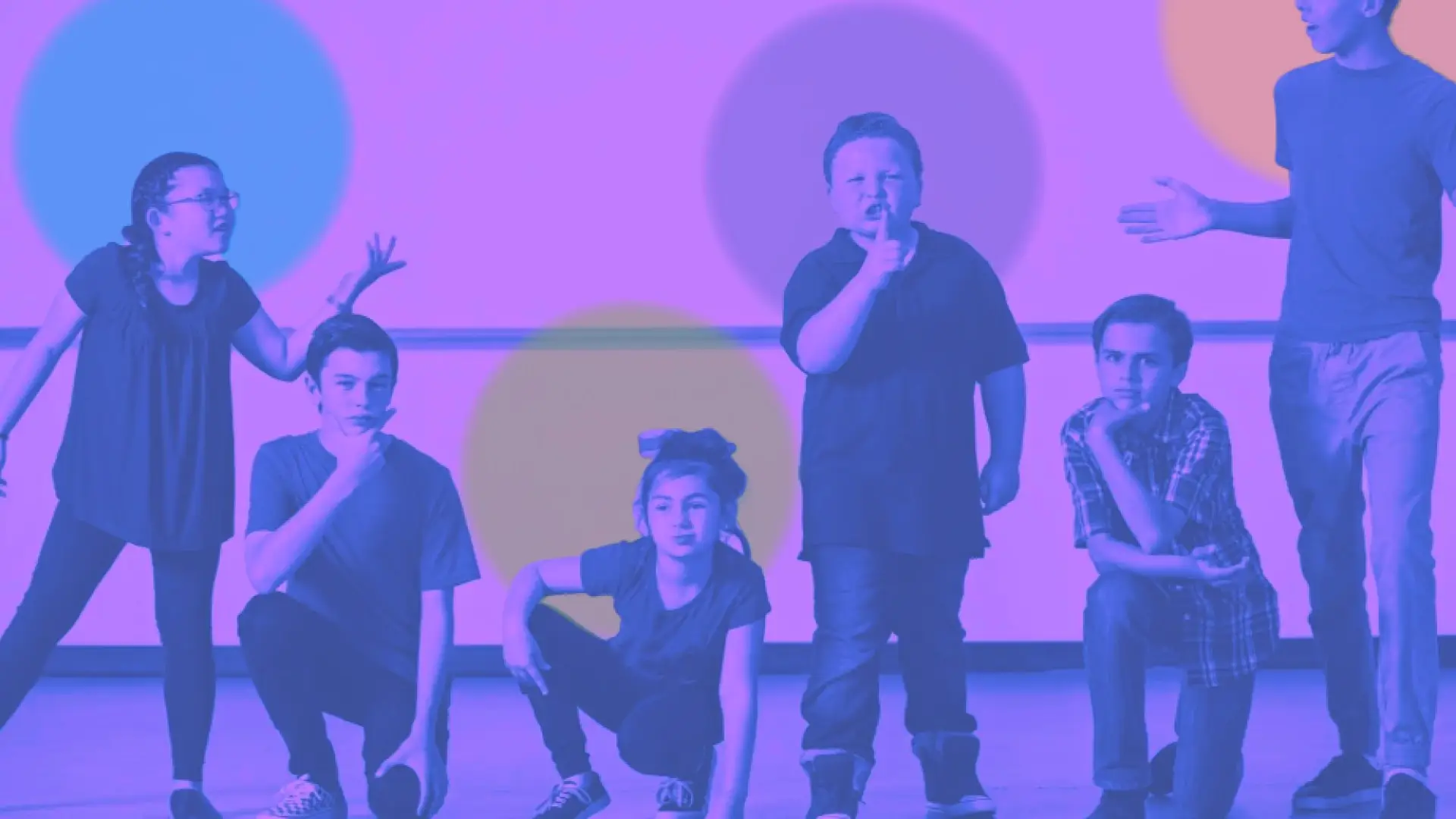 Line-up of children striking poses under a colorful but mostly purple scrim