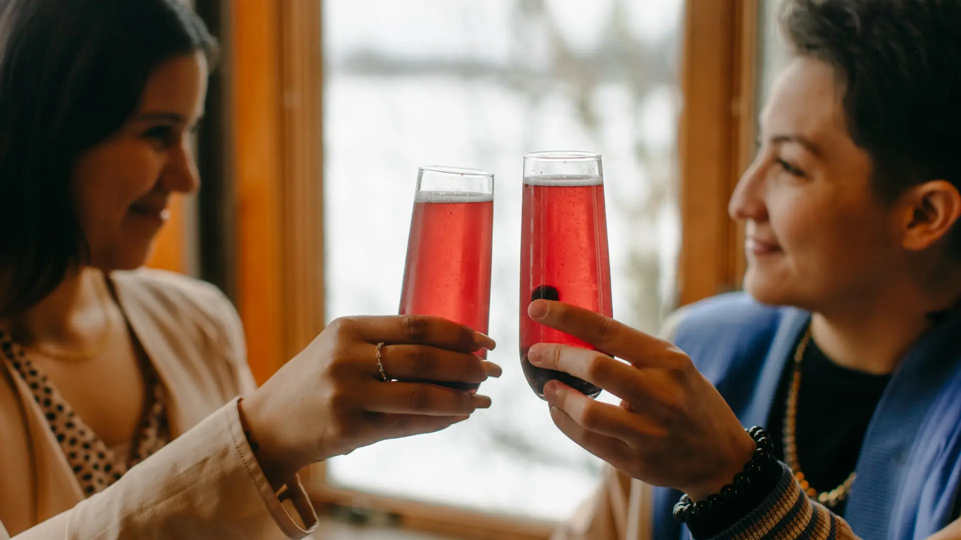 Two women raising their drinks and smiling.