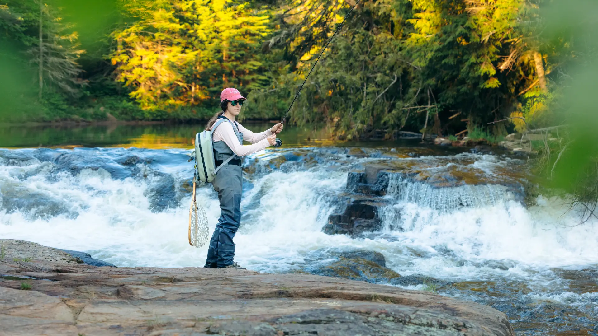 Someone fly fishing on the bank of a rocky river