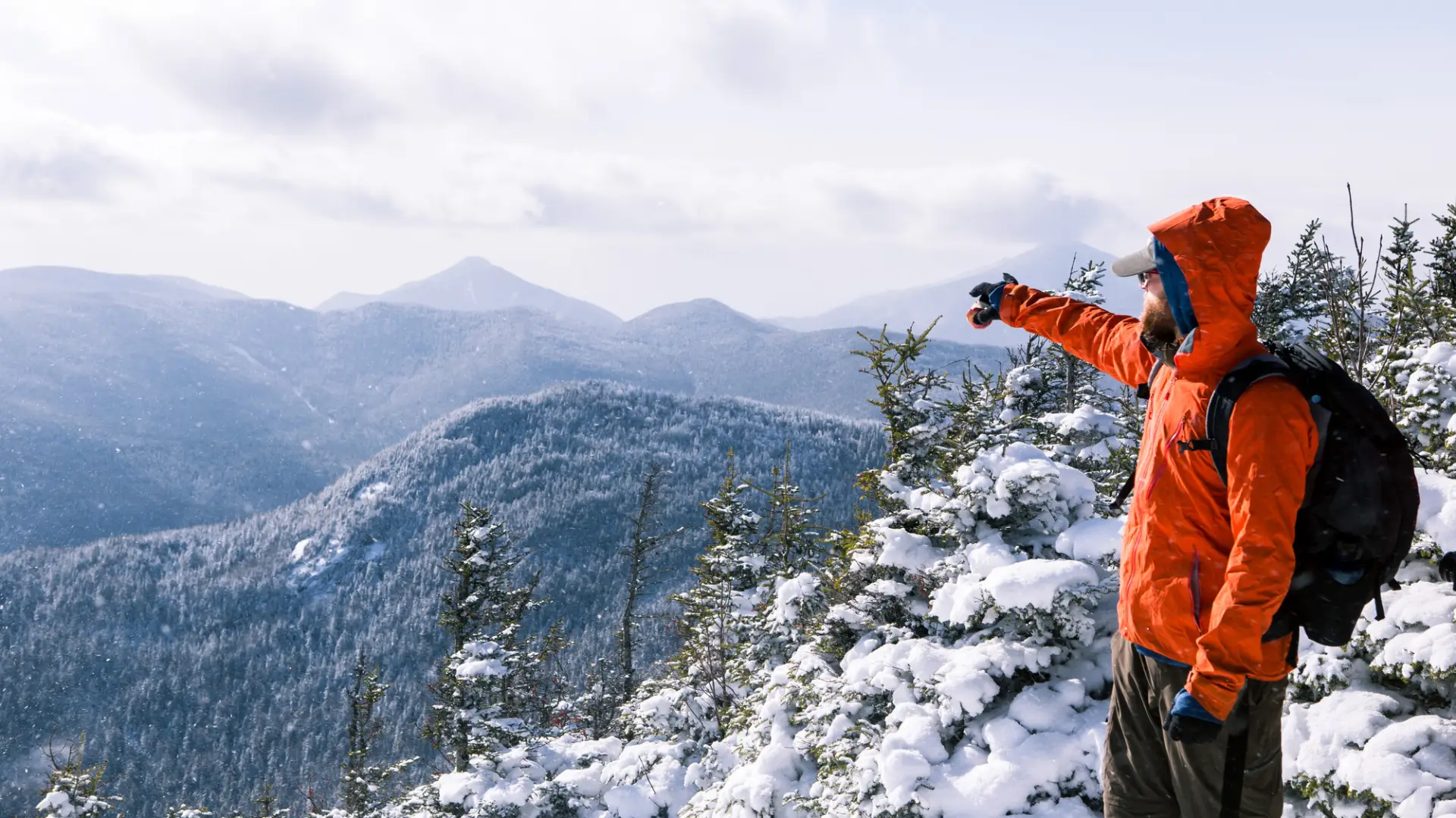 A guy points to other mountains from the top of Big Slide