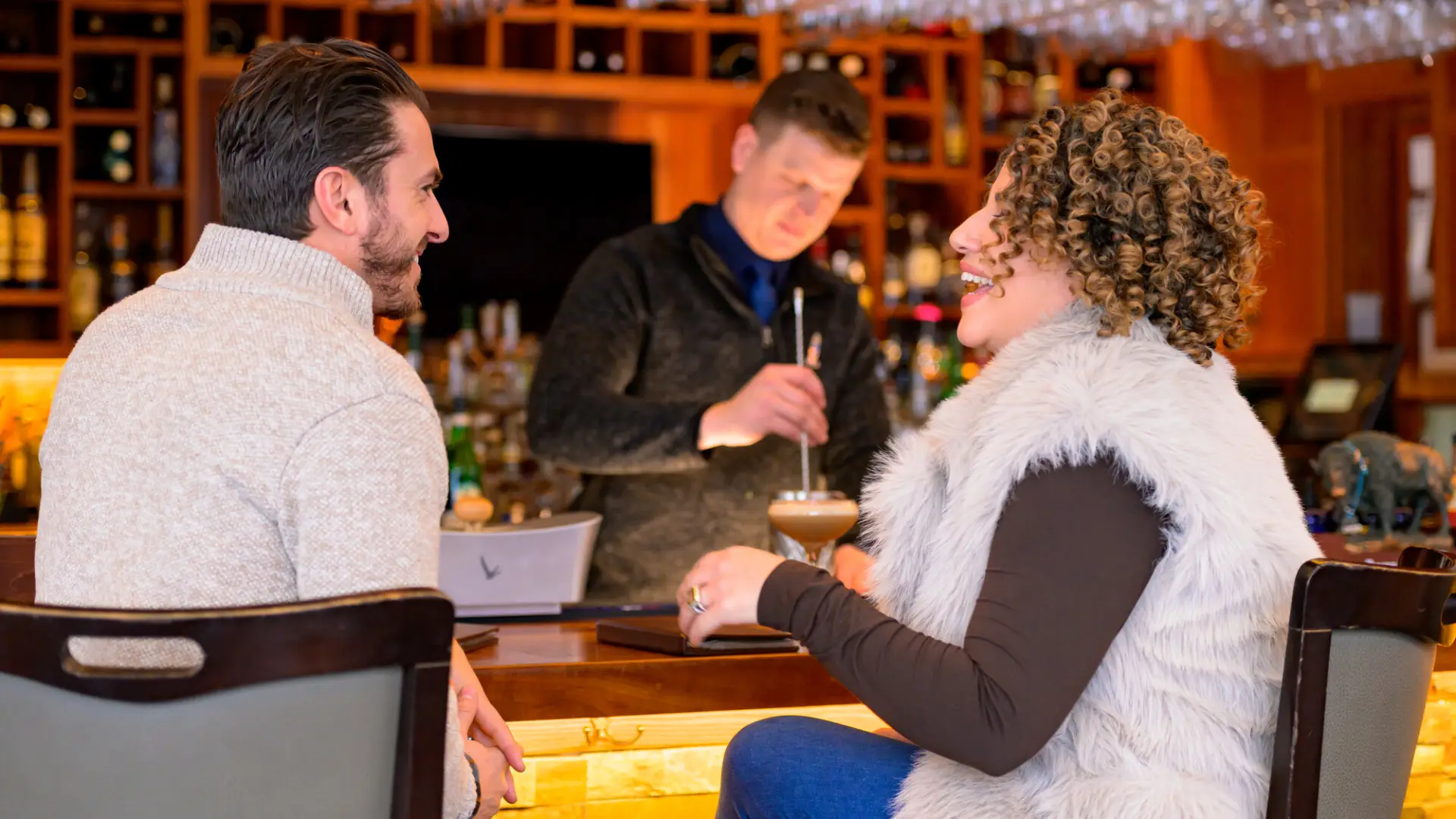 A man and woman enjoy drinks and food at a bar.