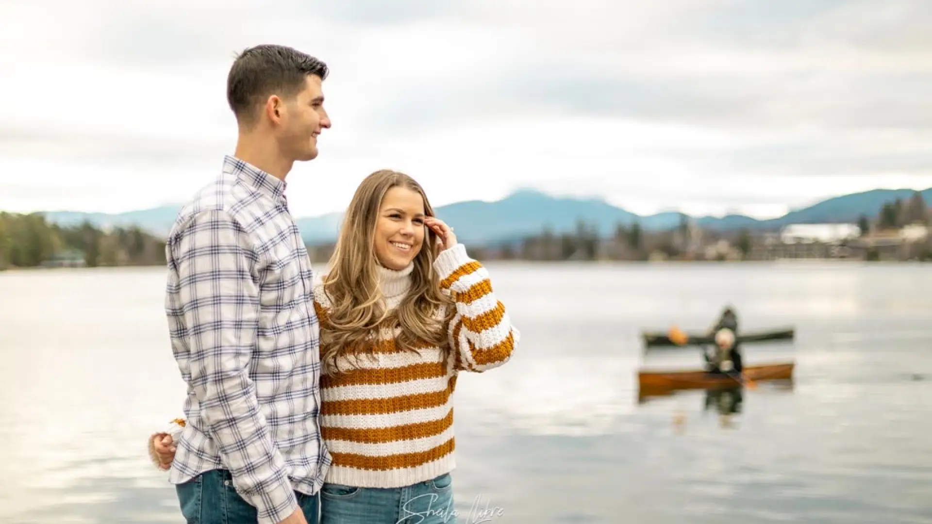 Man and woman at waters edge smiling.