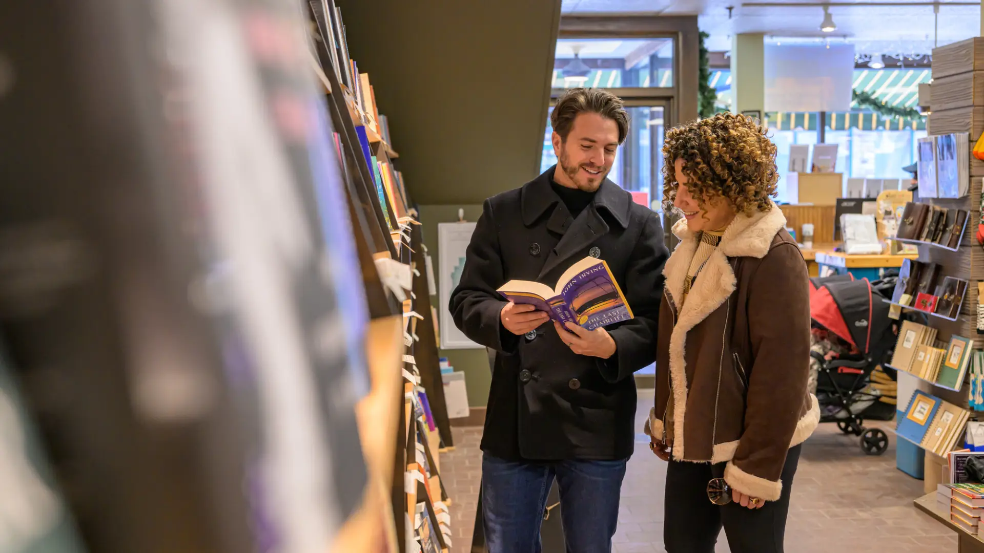 Man and woman look at open book together in aisle of bookstore