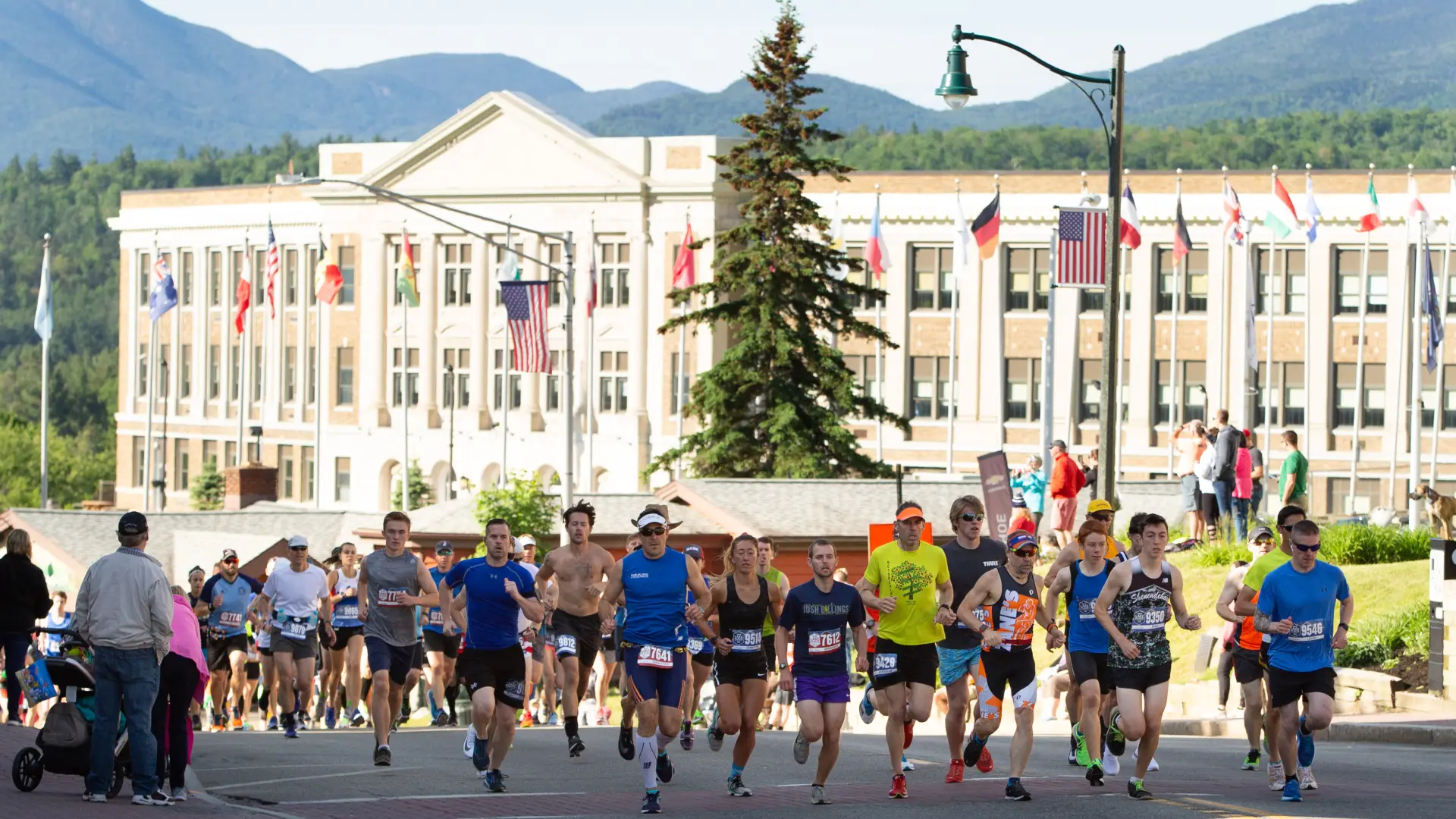 Runners race down a road as spectators look on.
