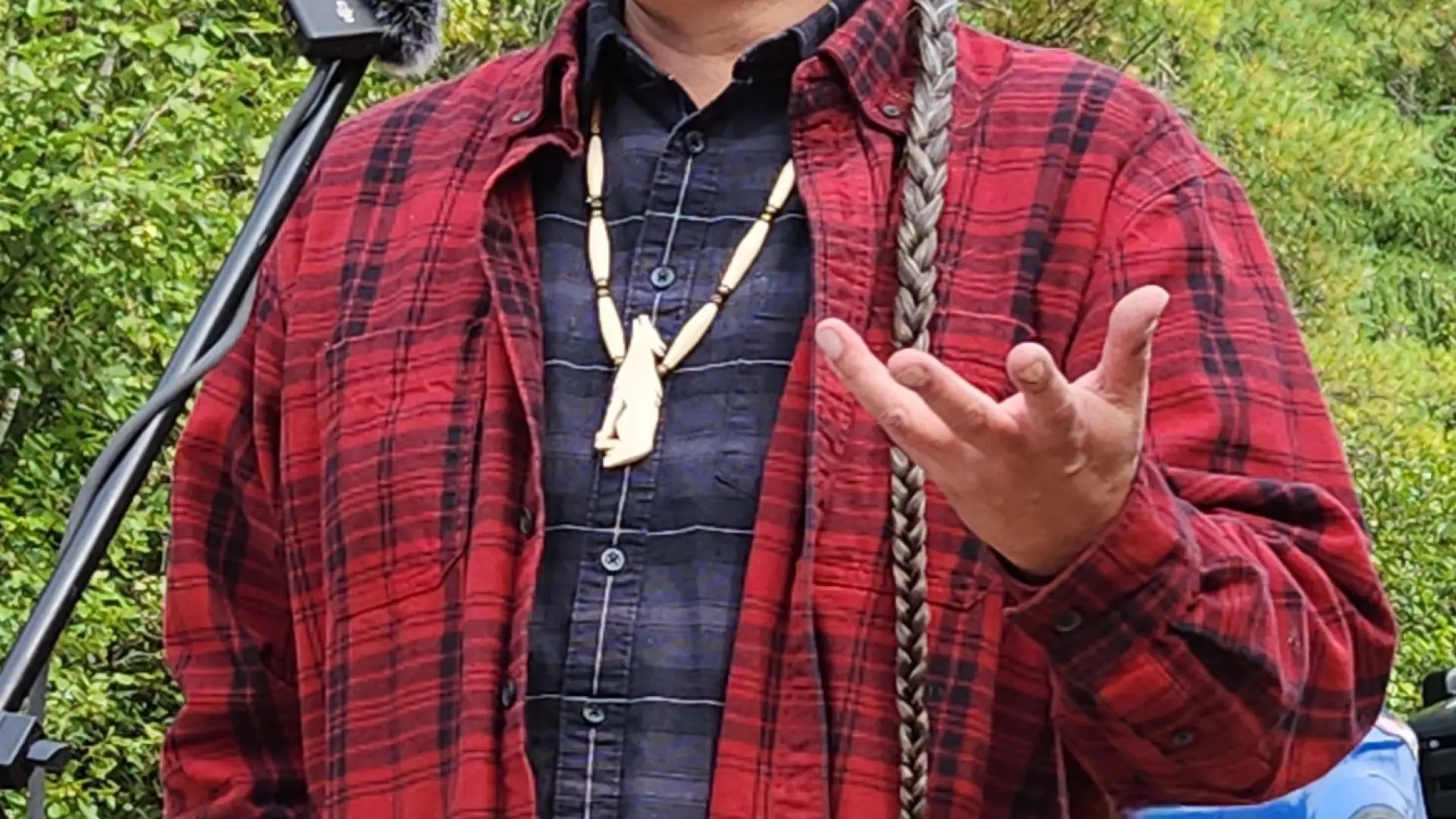 David Kanietakeron Fadden speaks into a microphone wearing a red plaid flannel