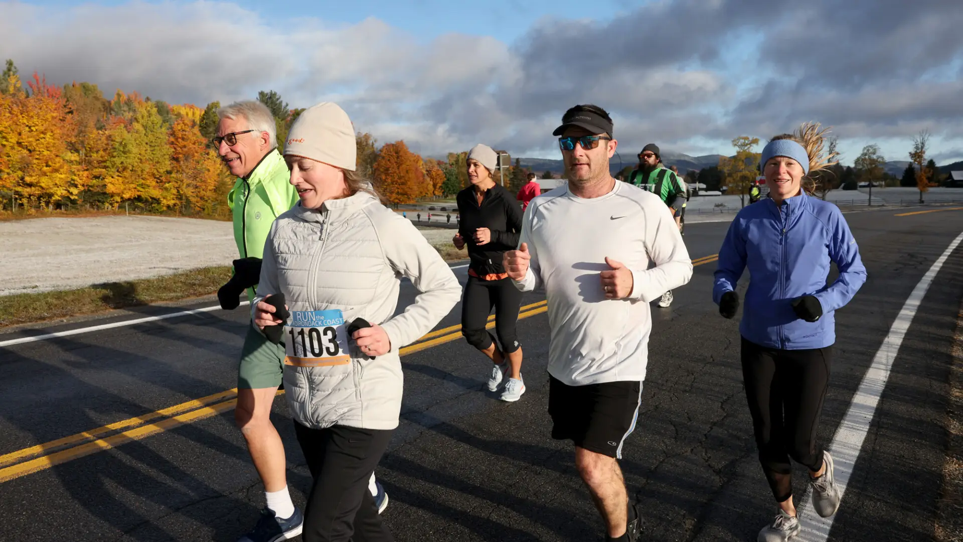 Group of runners on road with frosty fall foliage backdrop