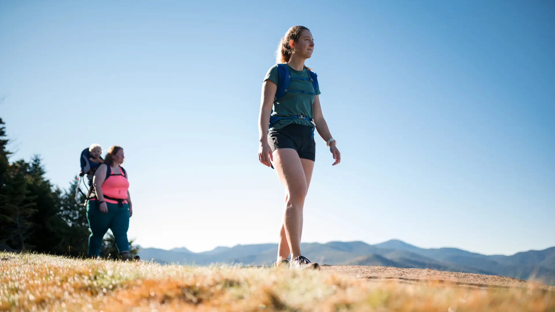 two women walk on top of a mountain.