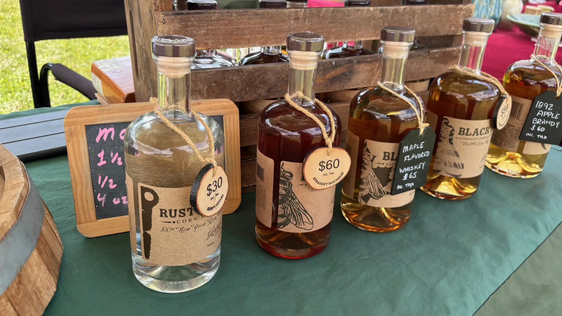 Gristmill's Black Fly bourbon and its delicious flavored variants displayed on a table at the Keene Valley Farmer's Market