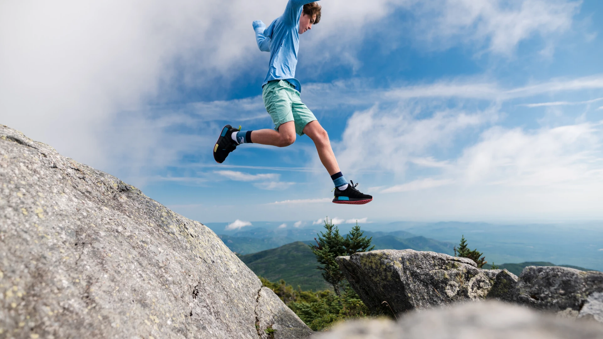 A young boy jumps from a rock.