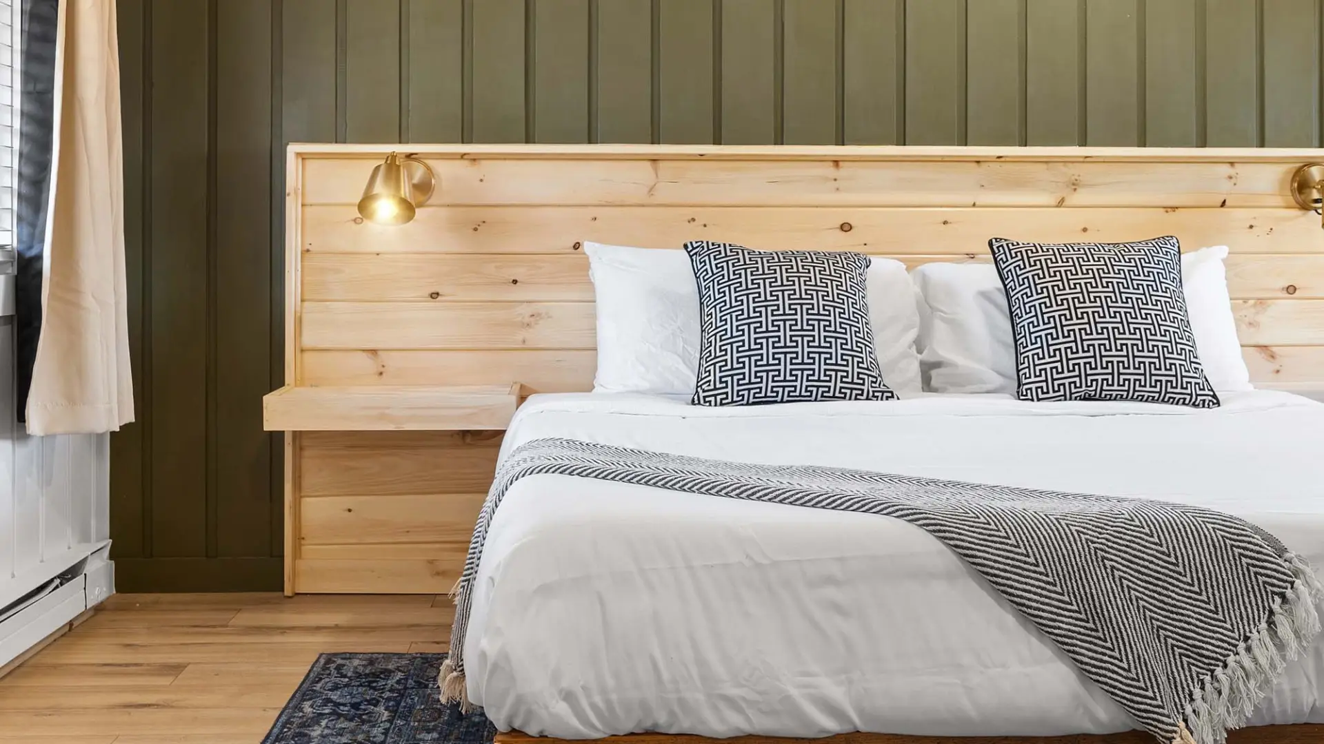 A white bed next to a green wall in a simply decorated room.