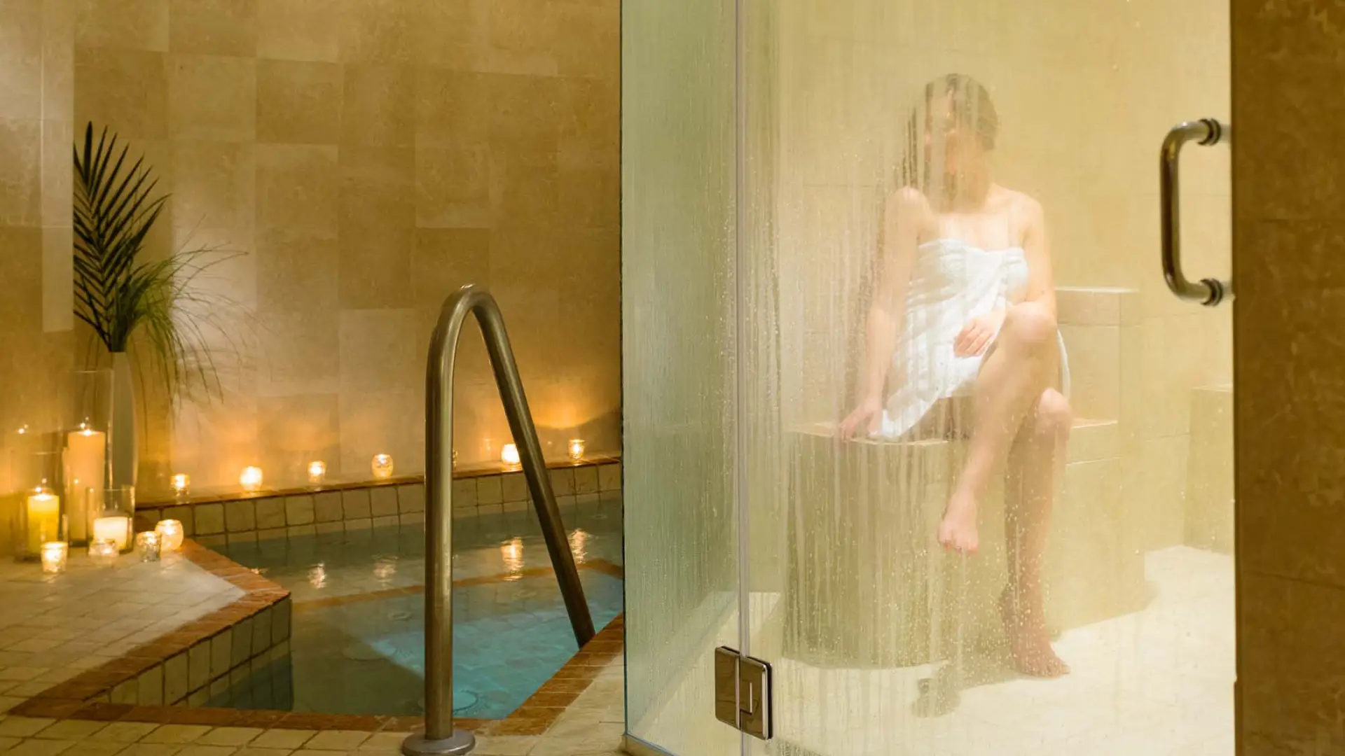 A woman sits wrapped in a lush towel while basking in the rejuvenating steam room.