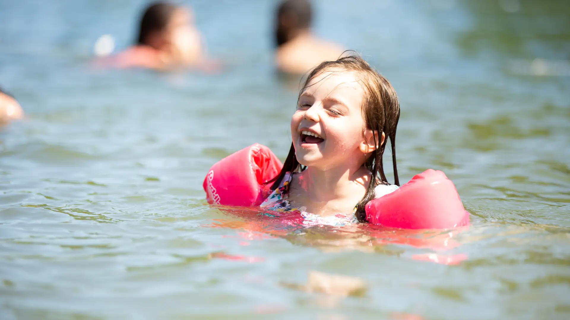 A girl in water wings laughs at the Mirror Lake Beach.