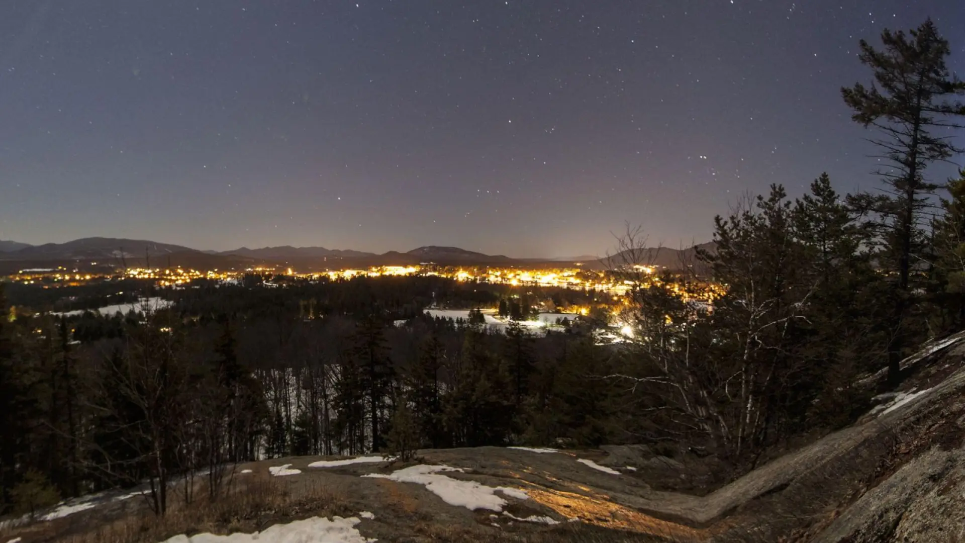 Night view of Lake Placid Village from Cobble Hill, with the High Peaks in the background on a starry-starry night