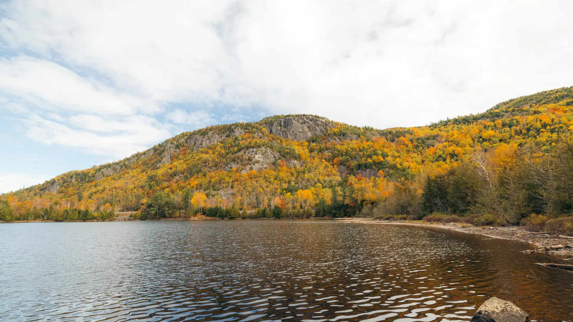 pond surrounded by rolling mountains with fall foliage