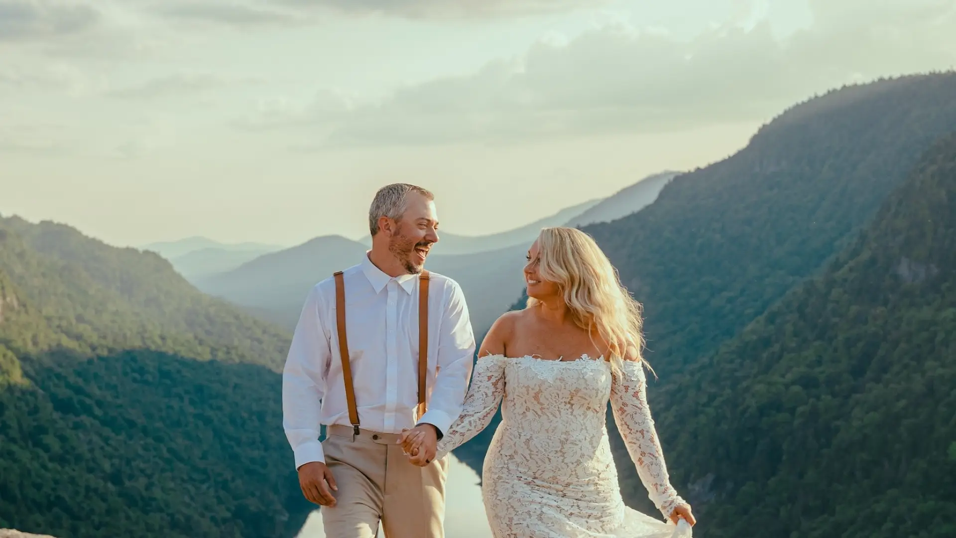Smiling bride and groom with the valley and mountains surrounding them in the background