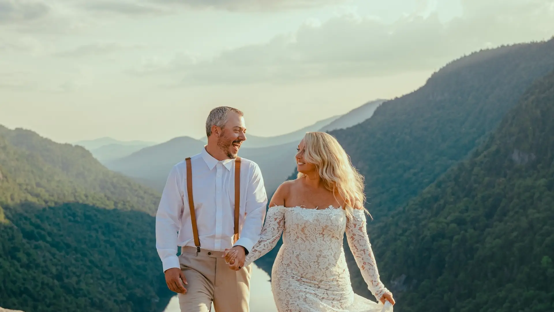 Smiling bride and groom with the valley and mountains surrounding them in the background