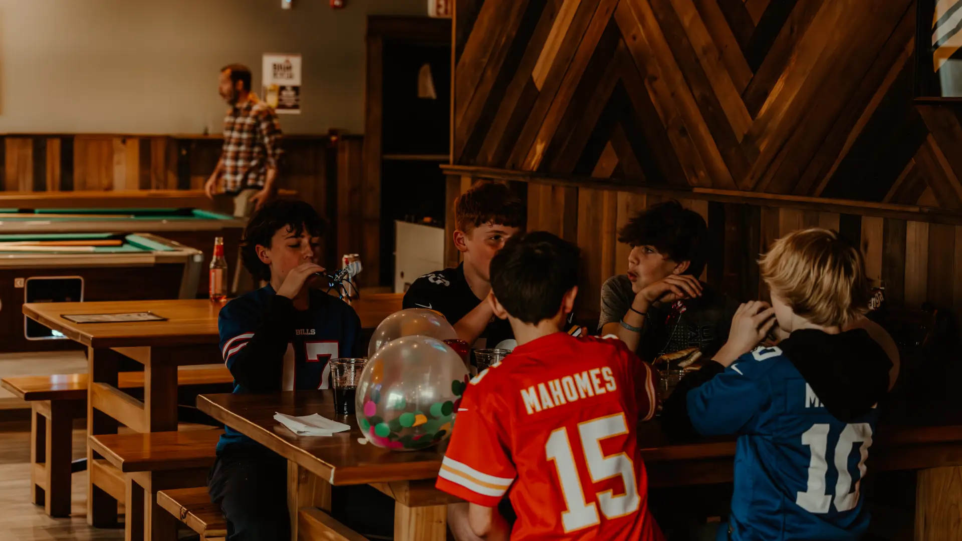 A table full of young boys celebrate in their jerseys.