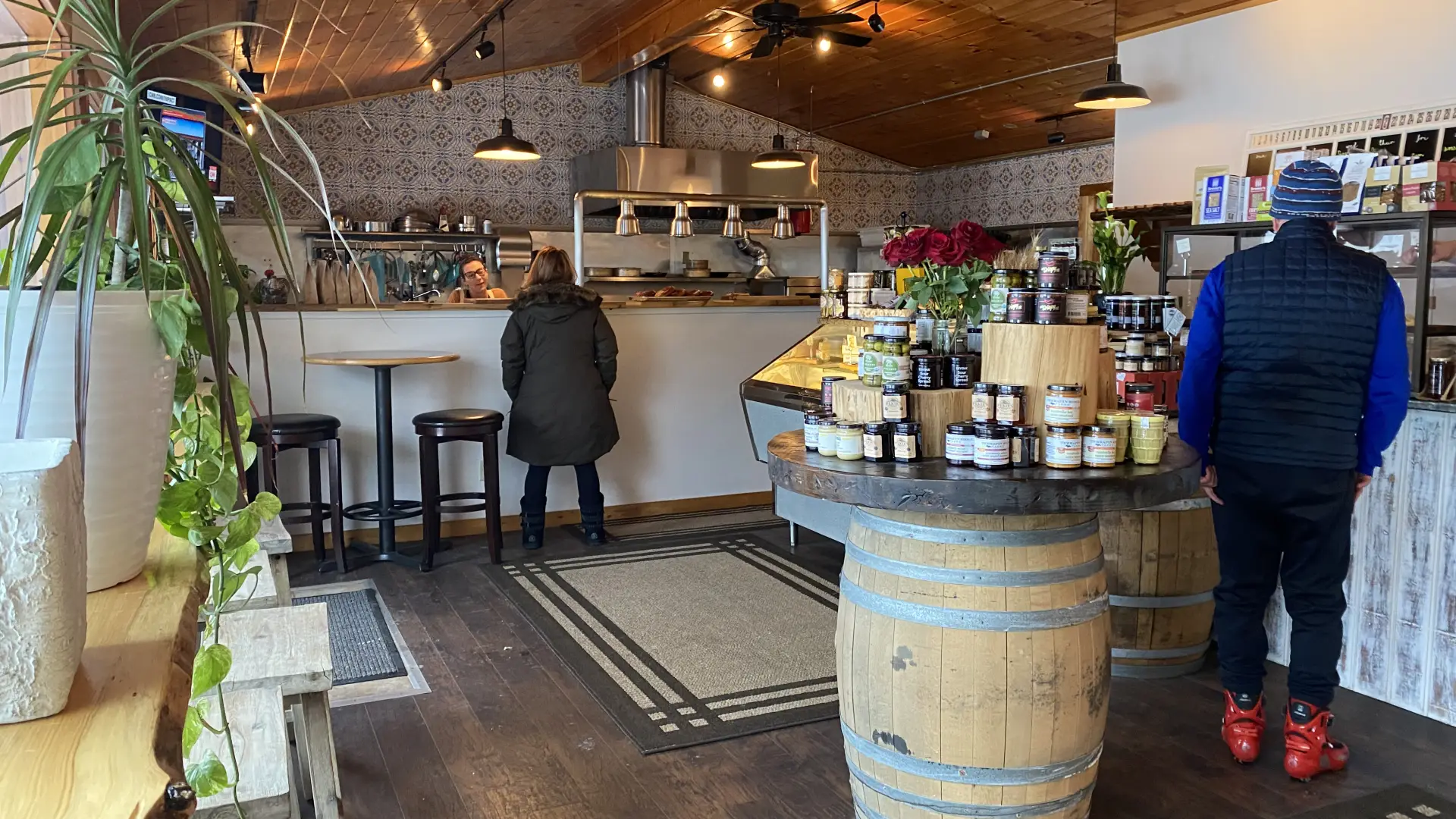 People line up inside a cozy bakery for pastries and cheese.