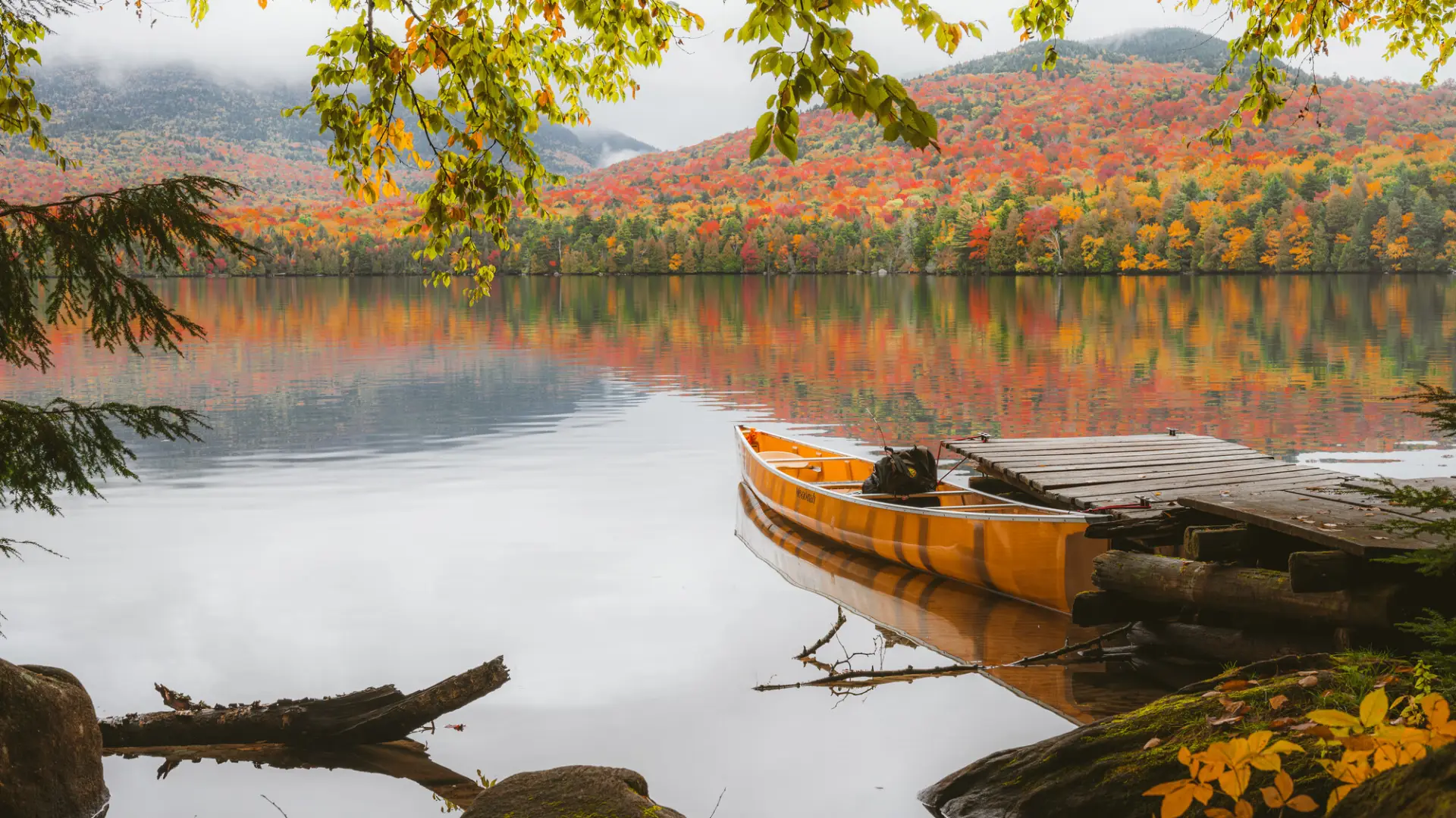 A canoe on a lake with fall scenery.