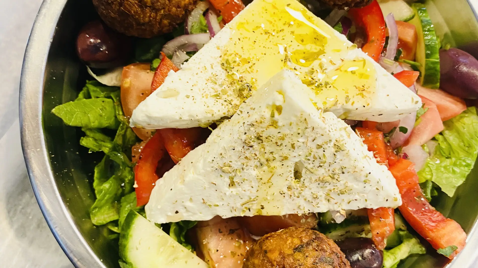 Greek salad with Lettuce, Cucumber, Tomato, Red Onion, Grape Leaves, Red Peppers, Olives, and Feta Cheese, tossed with House Greek Dressing and added Falafel.