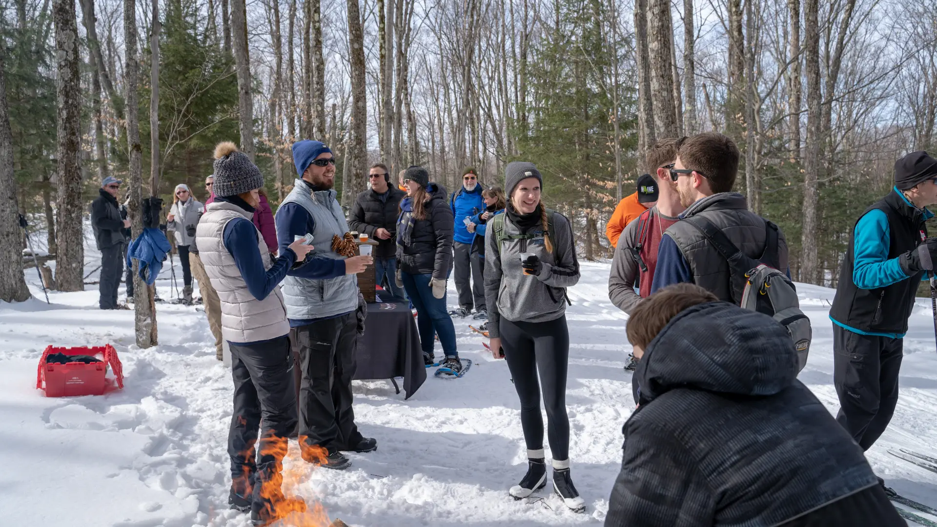 Cross-country skiers enjoying brews by a fire.