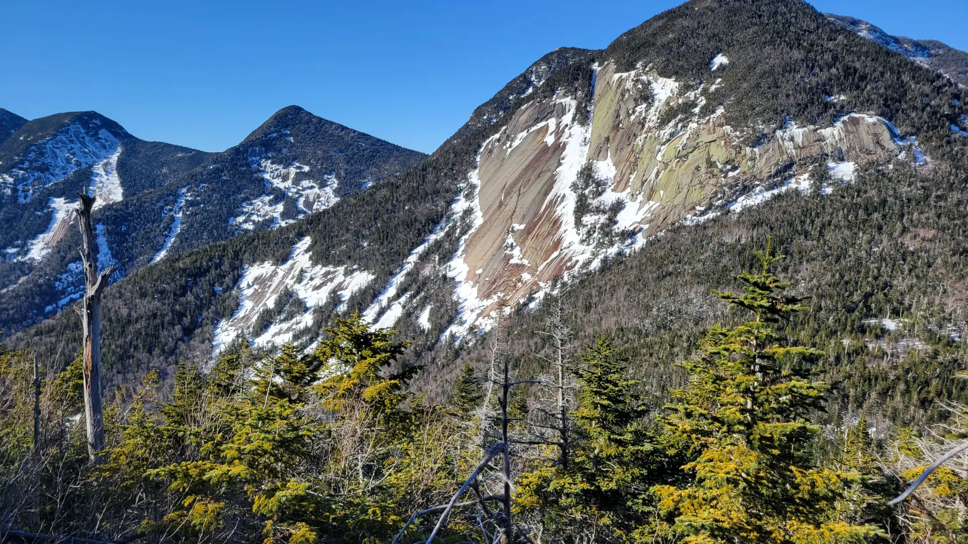 The view of mountains with large rock slabs with some snow on them.