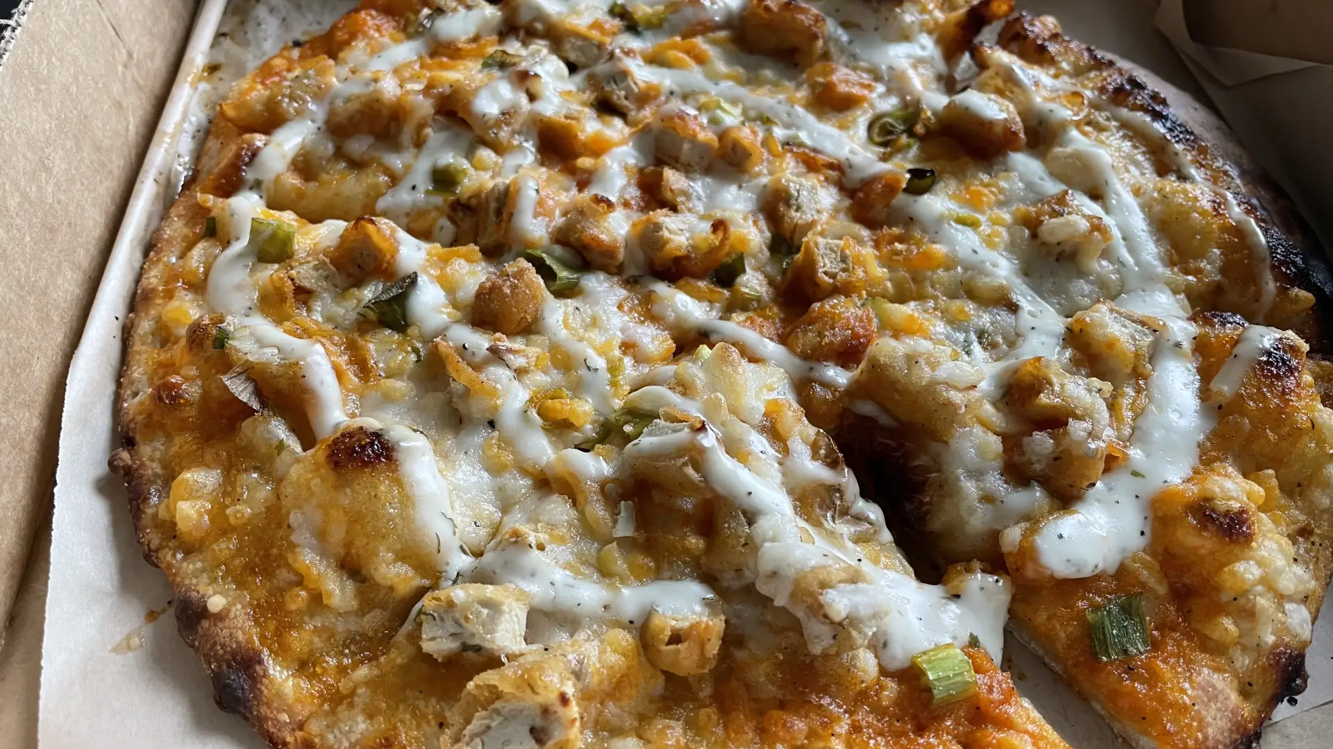Vegan Buffalo &quot;chicken&quot; pizza baked with a drizzle of vegan &quot;blue cheese&quot; on top.