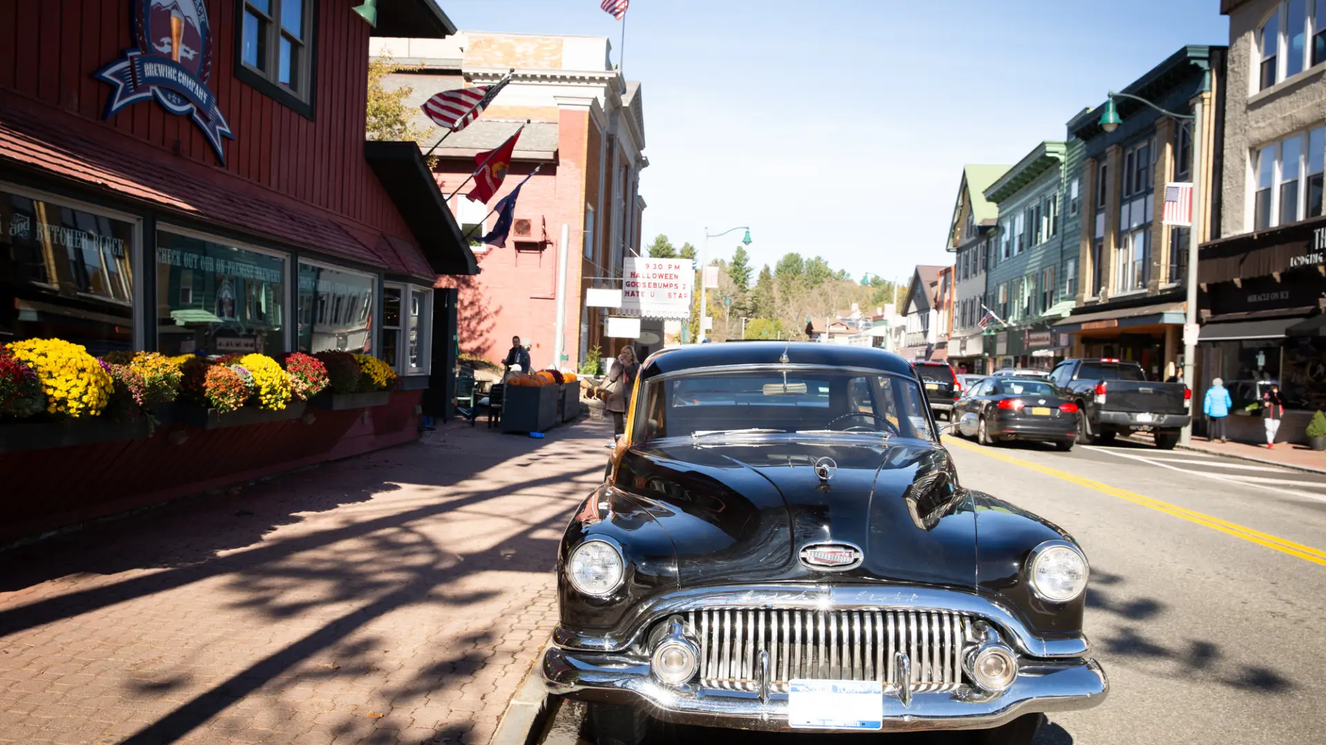 A vintage black car is parked on a small town Main Street.