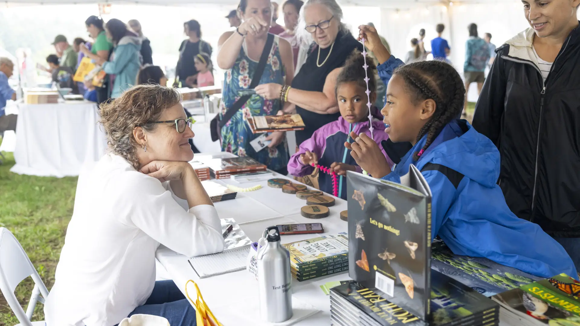 Young children and adults stand at book signing table talking to author