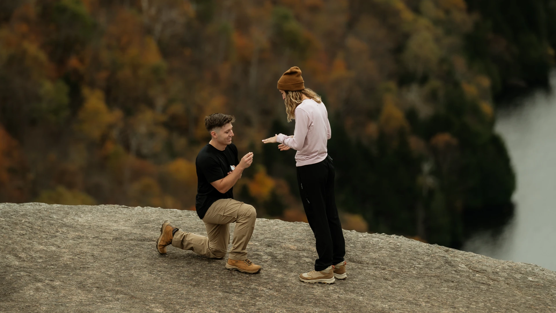 Mountain top engagement with a man on one knee overlooking a lake