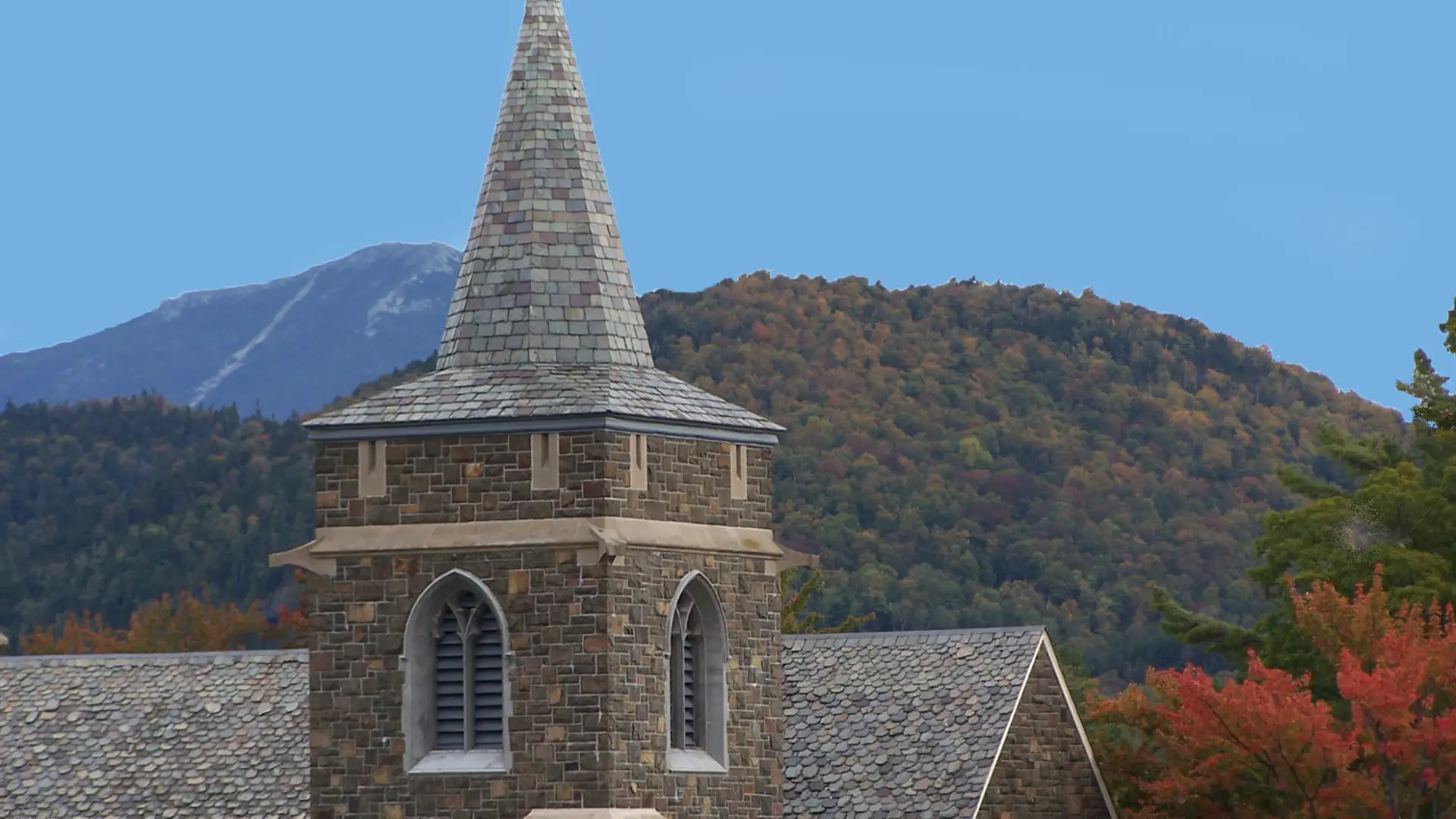 A church steeple among fall foliage. 
