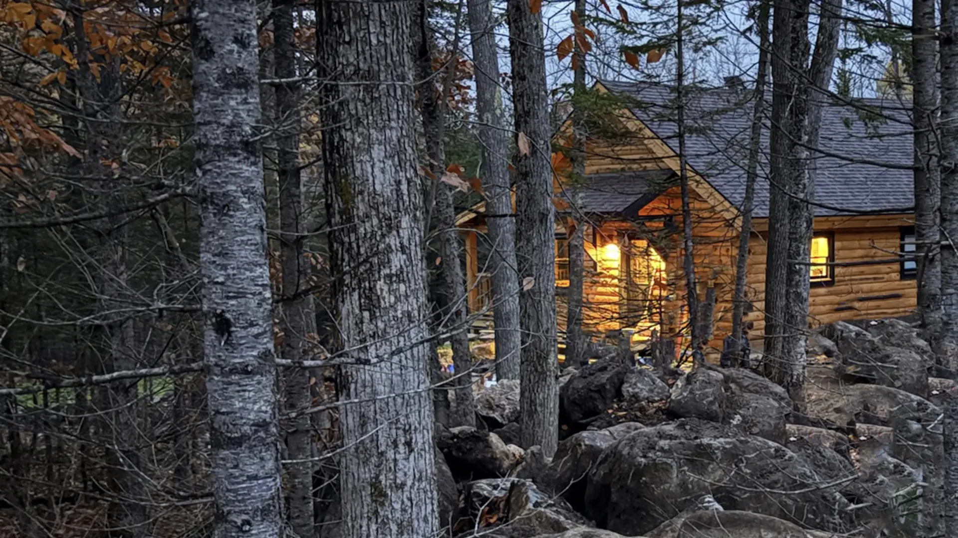 The warm glow of a log cabin through the trees.