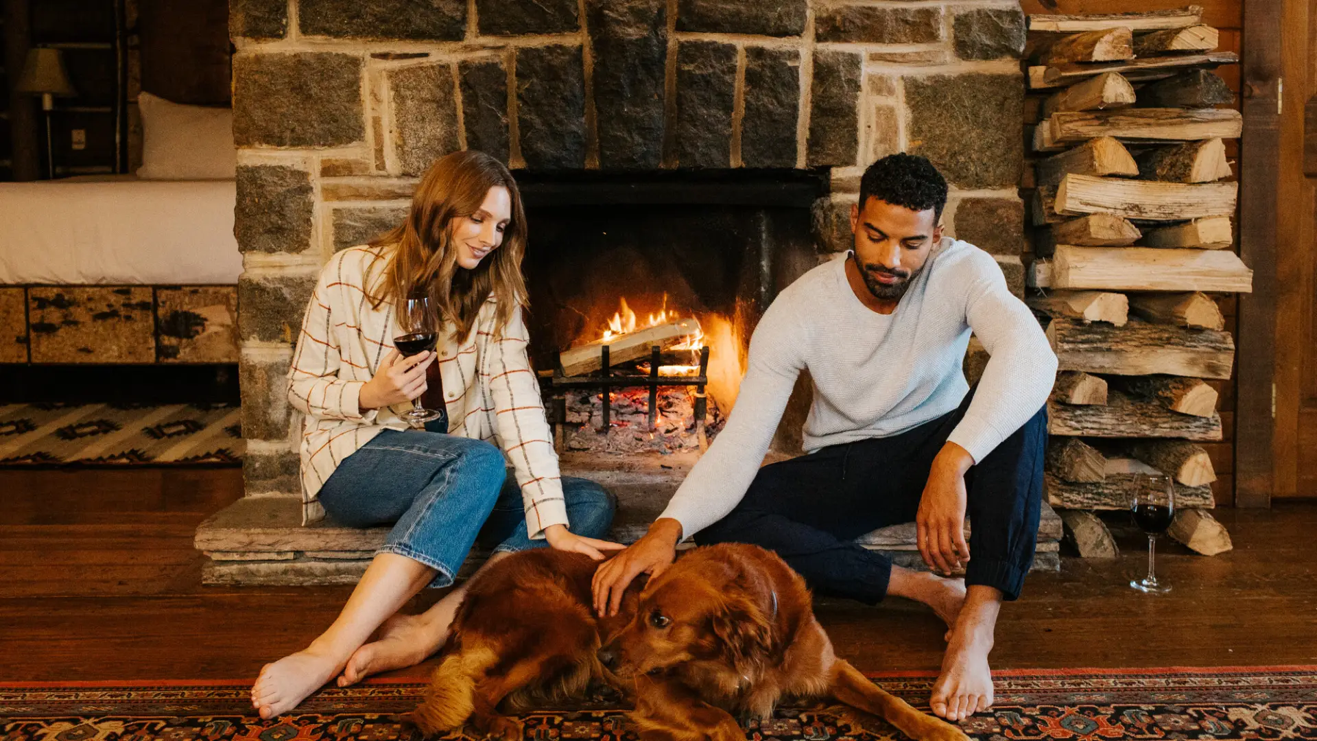 A couple sitting in front of a fireplace with a dog.