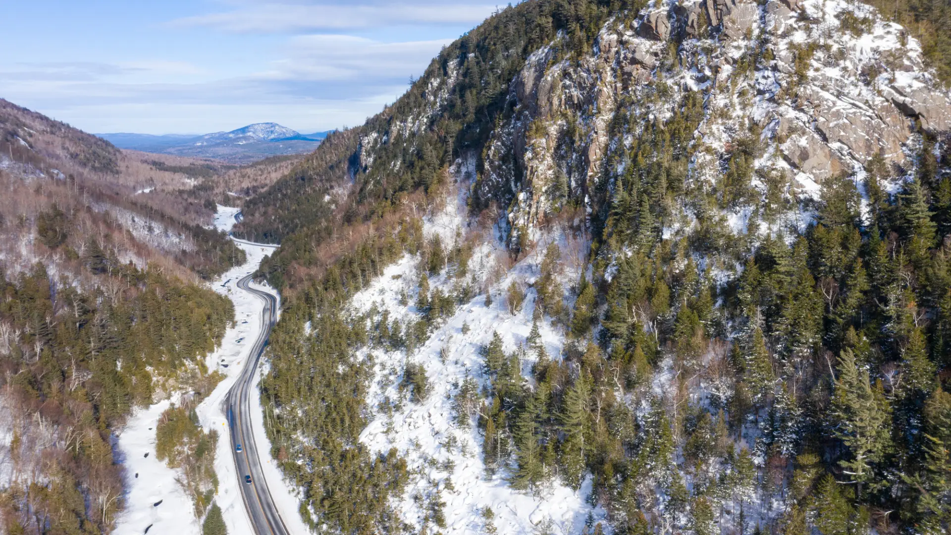 An aerial view of a road winding through a rocky-sided mountain pass.
