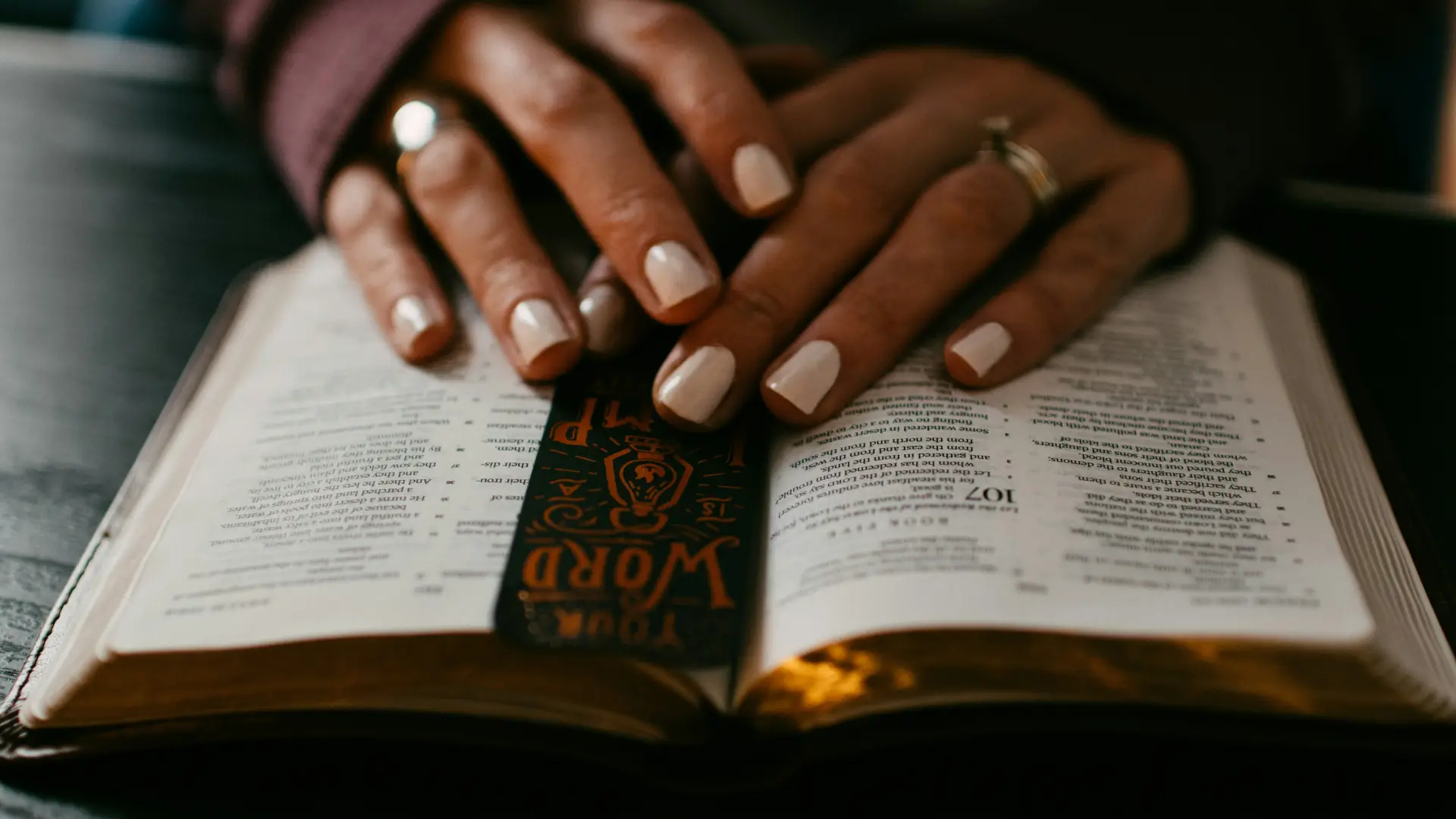 woman's hands on open bible with bookmark